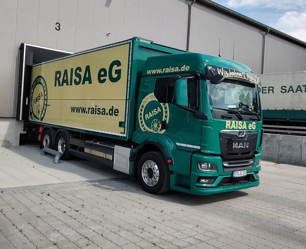 RAISA eG LKW steht an einer Verladerampe eines Logistikzentrums und wird am Tor 3 entladen.